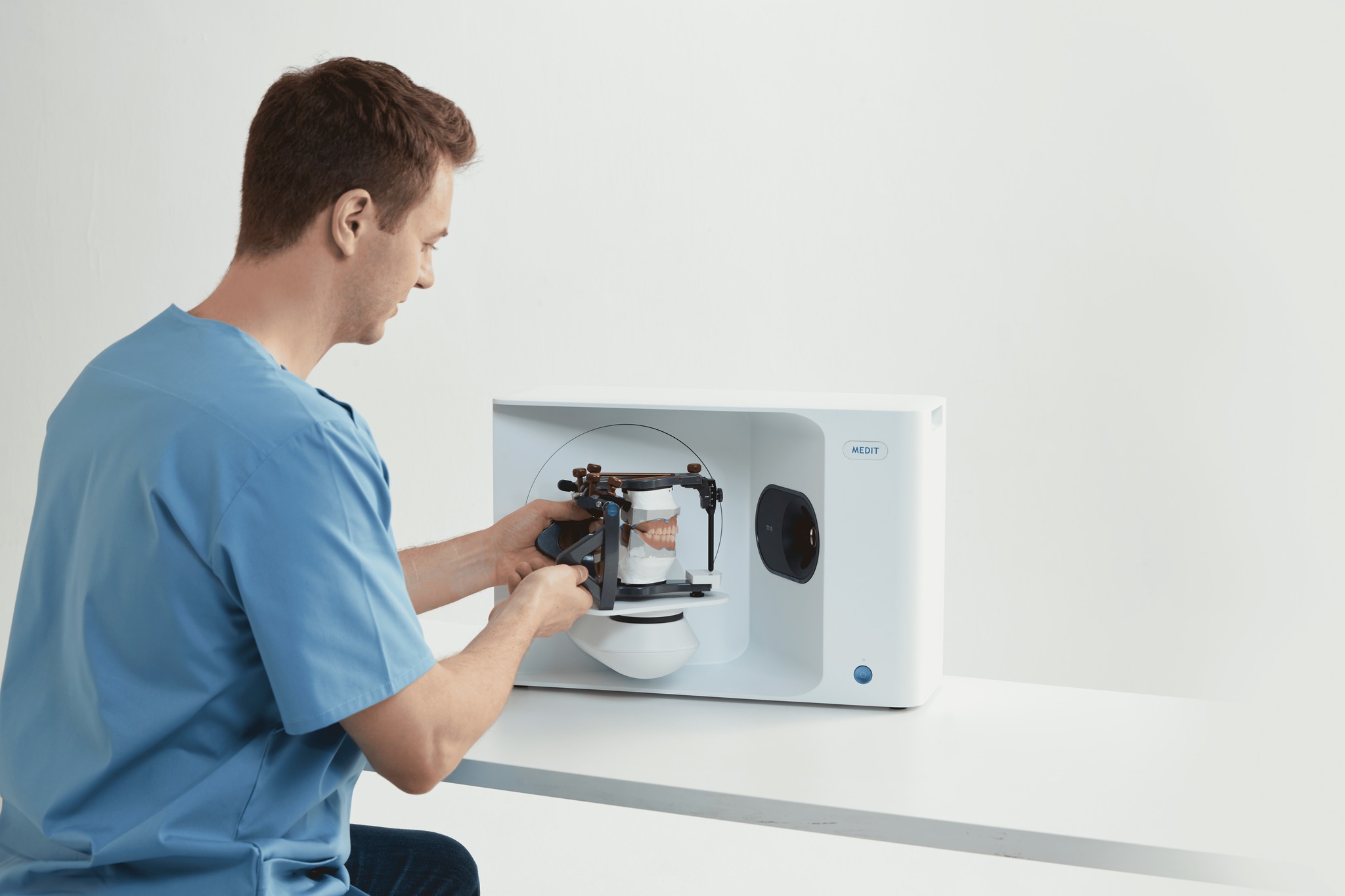Dental technician loading articulator into Medit scanner